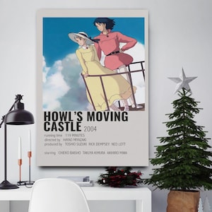 May include: A framed poster for the animated film "Howl's Moving Castle" with two characters on a balcony against a cloudy sky. The poster includes the film's title, year, and credits. A Christmas tree and desk lamp are in the foreground.