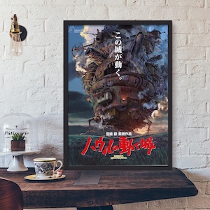 May include: Framed poster featuring a detailed illustration of a moving castle with Japanese text. The castle is a complex structure with mechanical elements, set against a blue sky and green landscape. The title "Howl's Moving Castle" is in red.