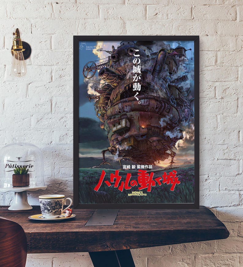 May include: Framed poster featuring a detailed illustration of a moving castle with Japanese text. The castle is a complex structure with mechanical elements, set against a blue sky and green landscape. The title "Howl's Moving Castle" is in red.