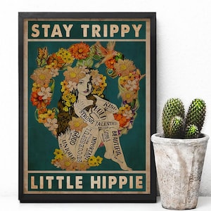 Può includere: Un poster incorniciato con le parole "STAY TRIPPY" e "LITTLE HIPPIE". L'opera presenta una donna circondata da fiori, con parole come "BOLD" e "BEAUTIFUL" sul suo corpo. Un cactus in vaso è a destra.