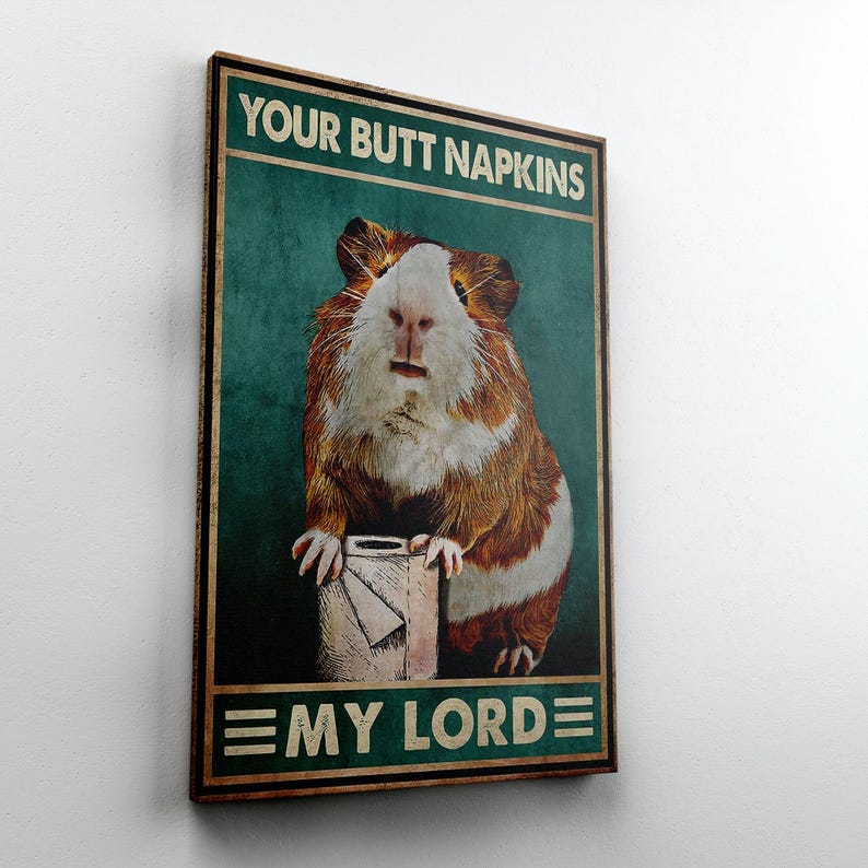 May include: A framed poster with the text "YOUR BUTT NAPKINS" at the top and "EMY LORDE" at the bottom. The poster features a guinea pig holding a roll of toilet paper. The guinea pig has brown and white fur.