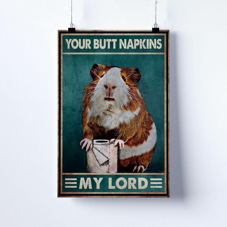 May include: A framed poster featuring a guinea pig with brown and white fur, holding a roll of toilet paper. The poster has the text "YOUR BUTT NAPKINS" at the top and "EMY LORD" at the bottom, set against a teal background.