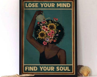 May include: A framed art print featuring a woman with a floral head and the text "LOSE YOUR MIND" above "FIND YOUR SOUL". The woman is depicted in a black dress, with a watering can pouring water onto the flowers. The background is teal.