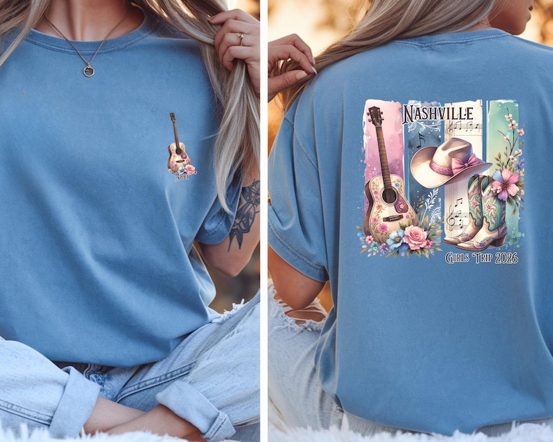 May include: A light blue t-shirt featuring a small guitar and floral design on the front. The back of the shirt displays a larger graphic with a guitar, cowboy hat, boots, and the text "Nashville Girls Tour 2026".