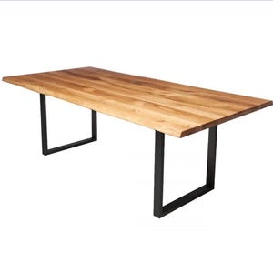Könnte beinhalten: Ein rechteckiger Holztisch mit natürlicher Holzmaserung. Der Tisch wird von schwarzen Metallbeinen in U-Form getragen. Die Abmessungen des Tisches betragen ca. 183 cm lang und 91 cm breit.