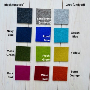 May include: A color chart of felt squares in various colors, including black, grey, sandbrown, navy blue, royal blue, ocean blue, moss green, fresh green, yellow, dark pink, wine red, and burnt orange. The felt squares are arranged in three rows of four squares each.