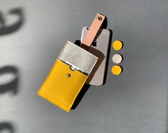 May include: A yellow felt phone case with a gray felt pocket and a pink felt strap. The case is open and a card is visible inside. Three felt circles are in the background.