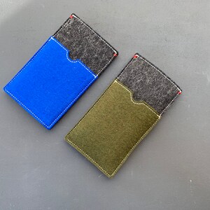 May include: Two felt phone cases, one blue and one green, with a black felt pocket on the front of each.