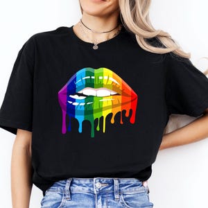May include: Black t-shirt with a colourful rainbow lips graphic, featuring a dripping paint effect. The design incorporates red, orange, yellow, green, blue, and purple hues. The shirt is made of a soft material and is suitable for casual wear.