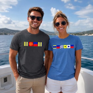 May include: Two people wearing t-shirts with nautical flag designs. One shirt is dark grey with a yellow, red, and blue flag pattern. The other is blue with a yellow, black and white checkered, and red flag pattern. Both are short-sleeved.