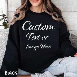 Peut inclure: Un sweat-shirt noir à manches longues et col rond avec le texte blanc Custom Text or Image Here imprimé en police cursive sur la poitrine. Le vêtement présente une coupe standard avec des poignets et un col côtelés, en noir uni.