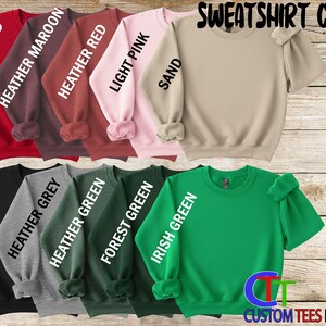 a collection of colorful sweatshirt colors, including red, pink, light pink, sand, and various shades of green, grey, and forest green.
