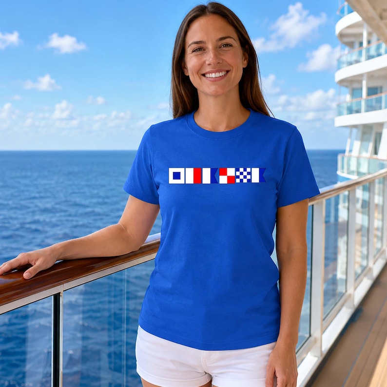 May include: A royal blue t-shirt with a horizontal design of nautical signal flags in white, red, and blue. The flags are displayed across the chest. The shirt is made of a soft material.