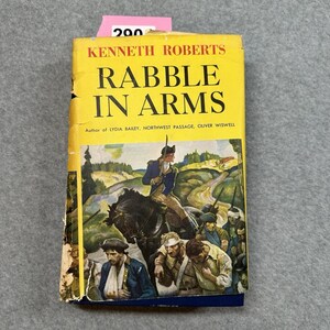 May include: A vintage hardcover book titled "Rabble in Arms" by Kenneth Roberts. The cover is yellow with black text and a historical illustration of soldiers and a rider on horseback. A pink price tag is attached to the top.