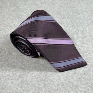 Puede incluir: Corbata enrollada con fondo burdeos oscuro y rayas horizontales en morado claro y azul. La corbata tiene un sutil patrón de espiga y está hecha de un material liso, posiblemente seda.