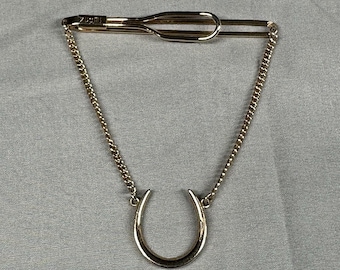 Pinza para corbata de herradura con cadena, estilo vintage, de la marca Swank, en tono dorado. Accesorio para hombre.