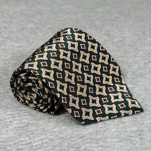 Könnte beinhalten: Aufgerollte Krawatte mit einem sich wiederholenden geometrischen Muster. Die Krawatte hat einen dunkelgrünen Hintergrund mit einem Muster aus roten, weißen und marineblauen Rauten. Die Krawatte ist aus einem glatten Material, möglicherweise Seide.