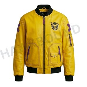 May include: A yellow bomber jacket with black ribbed collar, cuffs, and hem. It features a central zipper, two front pockets with purple pull tabs, a small flap pocket, a black and yellow bird emblem on the chest, and purple cross patches on sleeves.