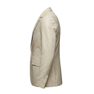 May include: A side view of a beige blazer. The blazer has a notched lapel, a two-button closure, and a single chest pocket. The sleeves have four buttons at the cuff. The blazer is made of a smooth, solid-colored fabric.