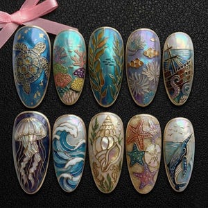 May include: Ten oval nail art designs with marine themes. Each nail features detailed designs of sea creatures, coral, and nautical elements in various colours, including blue, gold, and iridescent finishes. A pink ribbon is in the background.
