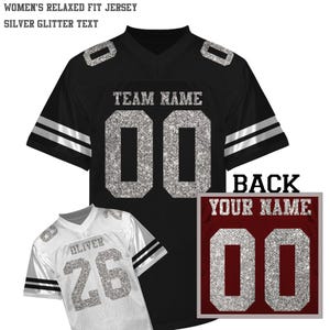 Könnte beinhalten: Schwarzes Football-Trikot mit silbernem Glitzertext und der Nummer "00". Das Trikot hat weiße Streifen auf den Ärmeln und Schulterpolstern. Ein weißes Trikot mit der Nummer "26" ist ebenfalls abgebildet. Der Text "TEAM NAME" ist sichtbar.