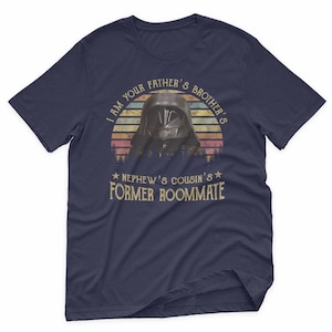 May include: Navy blue t-shirt featuring a graphic of a character's helmet against a sunset design. The text reads "I AM YOUR FATHER'S BROTHER'S NEPHEW'S COUSIN'S FORMER ROOMMATE".