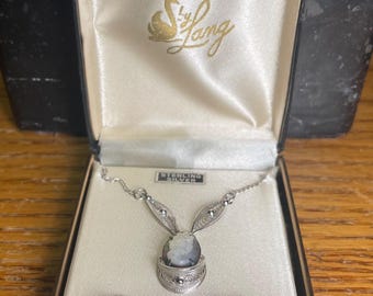 May include: A vintage jewelry set by Lang, featuring a necklace and matching earrings. The set includes a cameo pendant and earrings, all set in sterling silver. The jewelry is presented in a satin-lined box with the Lang logo.
