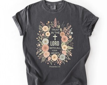 Peut inclure: T-shirt gris foncé avec un motif floral et le texte "Faites confiance au Seigneur de tout votre cœur" et une croix. Le motif comprend des fleurs et des feuilles aux couleurs pastel, avec le verset biblique Proverbes 3:5.