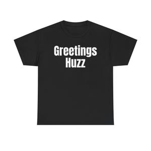 May include: A black short-sleeved t-shirt featuring the white text Greetings Huzz printed in a bold, sans-serif font across the center of the chest. The garment has a crew neckline and a standard fit with straight hemmed sleeves and bottom edge.