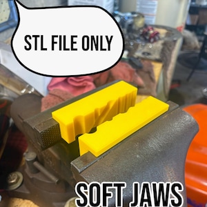 Puede incluir: Mordazas blandas amarillas brillantes sujetas en una prensa de metal. El texto "STL FILE ONLY" está en una burbuja sobre las mordazas, y el texto "SOFT JAWS" está debajo. Protegen las piezas de trabajo.