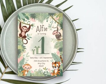 May include: A jungle-themed birthday invitation featuring the name "Alfie" and the number "1". The design includes illustrations of monkeys, a tiger, and lush greenery. The invitation is on a plate with palm leaves.