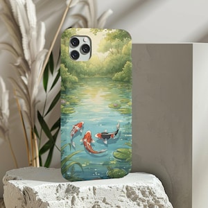 Puede incluir: Funda de teléfono con un diseño de estanque sereno y peces koi. El diseño incluye nenúfares, plantas acuáticas y un exuberante fondo de bosque verde. Los peces koi son de color naranja, blanco y negro, añadiendo un toque vibrante.
