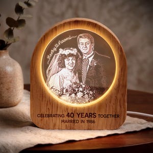 May include: An arched wooden light display featuring a circular illuminated portrait of a couple in wedding attire. The text reads Henry and Naomi, Celebrating 40 Years Together, Married in 1986. The light emits a warm glow around the central image.