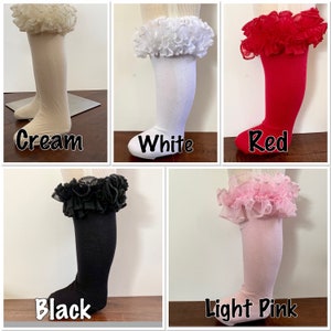 May include: Five pairs of knee-high socks in cream, white, red, black, and light pink. Each pair features a ruffled lace trim at the top. The colors are labeled with text in the image.