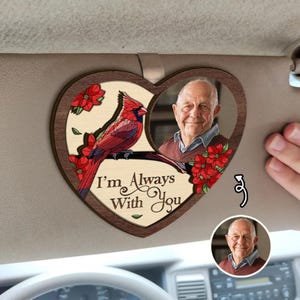 May include: A heart-shaped wooden car accessory featuring a photo of an older man and a red cardinal bird. The text "I'm Always With You" is printed on the wooden surface. Red flowers are also included in the design.