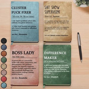 May include: Four notebooks with humorous definitions. The notebooks are in blue, tan, pink, and green. The text on the notebooks includes "CLUSTER FUCK FIXER", "SHIT SHOW SUPERVISOR", "BOSS LADY", and "DIFFERENCE MAKER". A silver pen is on the right.