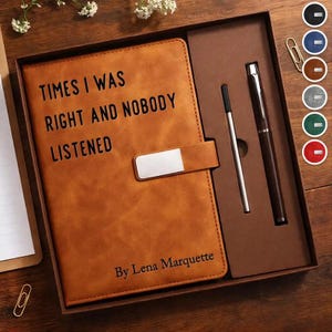 Könnte beinhalten: Ein braunes Lederjournal mit dem Text "TIMES I WAS RIGHT AND NOBODY LISTENED" und "By Lena Marquette" wird in einer Geschenkbox mit einem Stift und einem Stift gezeigt. Das Journal hat einen silbernen Verschluss.