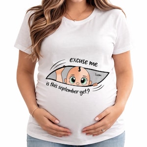 May include: White t-shirt with a graphic of a baby peeking out of a slit, with the text "excuse me is this september yet?" and the name "Liam". The baby has large green eyes and a small tuft of hair.