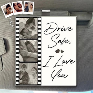 以下が含まれることがあります： 「Drive Safe, I Love You」のテキストが入った、白黒デザインの車のサンバイザー。3枚の白黒写真が入ったフィルムストリップが付いています。小さな写真も追加で添付されています。