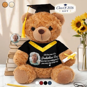 Op de afbeelding: Een bruine teddybeer met een afstudeerhoed en een zwart shirt met een foto en tekst. Op het shirt staat "On your Graduation Day know that I am walking beside you every step of the way." Een opgerold diploma wordt in zijn poot gehouden. De tekst "Class Of 2026 GIFT" is ook zichtbaar.