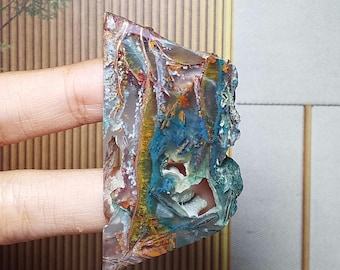 May include: A polished, irregular slab of agate featuring a vibrant mix of deep blue, golden yellow, and translucent gray bands. The stone displays intricate, natural crystalline formations and mineral inclusions throughout its textured surface.