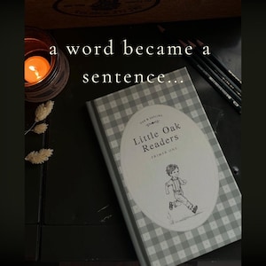 Puede incluir: Un libro titulado Little Oak Readers Primer One con una cubierta de cuadros grises y blancos. La cubierta presenta una etiqueta ovalada con una ilustraci&oacute;n en blanco y negro de un ni&ntilde;o corriendo. El texto a word became a sentence es visible.