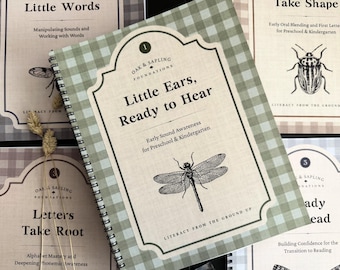 May include: A spiral-bound educational workbook titled Little Ears, Ready to Hear with a green and white gingham cover. The cover features a black line drawing of a dragonfly, the text Oak & Sapling Foundations, and Early Sound Awareness.