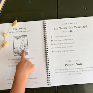 May include: An open spiral-bound educational workbook featuring the poem The Swing by Robert Louis Stevenson on the left page and a Week 2 Review section on the right page. The text includes practice goals like hearing rhyming words and a parent note.