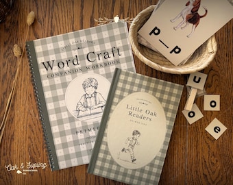 May include: A spiral-bound Word Craft Companion Workbook and a Little Oak Readers Primer One book, both featuring a gray and white gingham pattern, alongside a woven basket containing illustrated cards and several small square letter tiles.