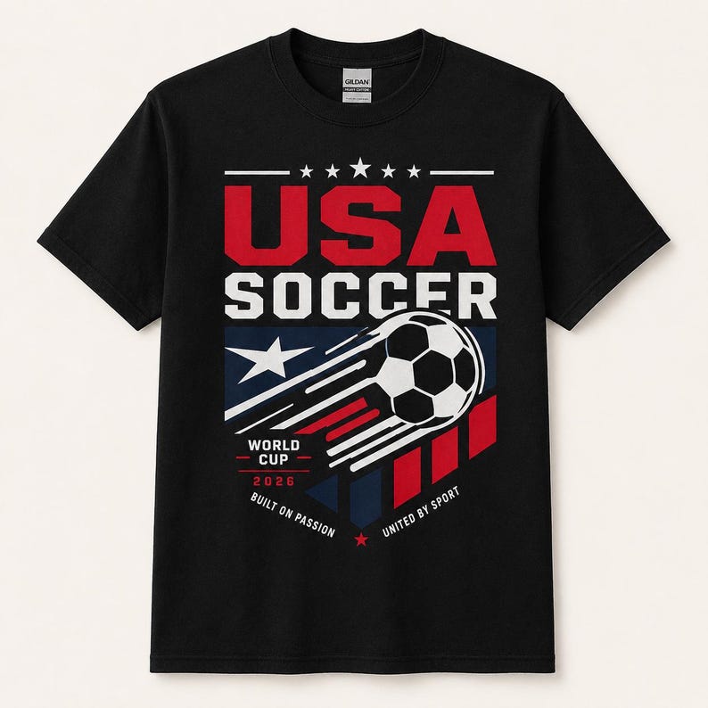 May include: Black t-shirt with a graphic design for USA Soccer. The design includes the text "USA SOCCER" in red and white, a soccer ball, and the text "WORLD CUP 2026". The shirt also has the phrases "BUILT ON PASSION" and "UNITED BY SPORT".