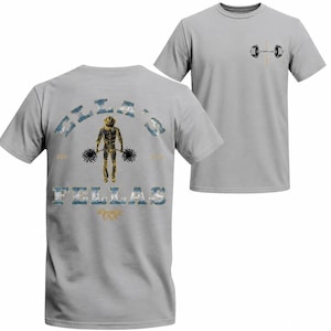 Puede incluir: Camiseta gris claro con un gráfico de levantador de pesas en la espalda, con el texto "ELLA'S FELLAS" y "USA". La parte delantera muestra un gráfico de barra y el texto "BARBELL.COM".