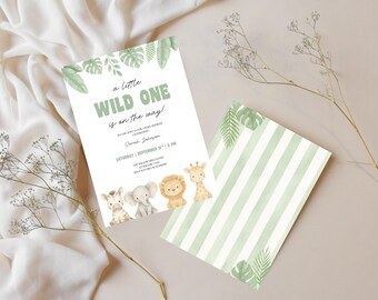 May include: Two-sided invitation with a jungle theme. The front features text "a little WILD ONE is on the way!" and jungle animal illustrations. The back has green and white stripes. The invitation is on a white background with a sprig of dried flowers.