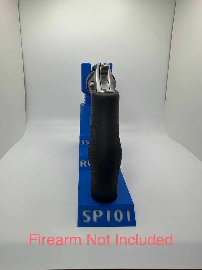 May include: A blue 3D-printed firearm stand with the text "SP101" and "35 R" on the side. A black-handled revolver is placed in the stand. The text "Firearm Not Included" is at the bottom.