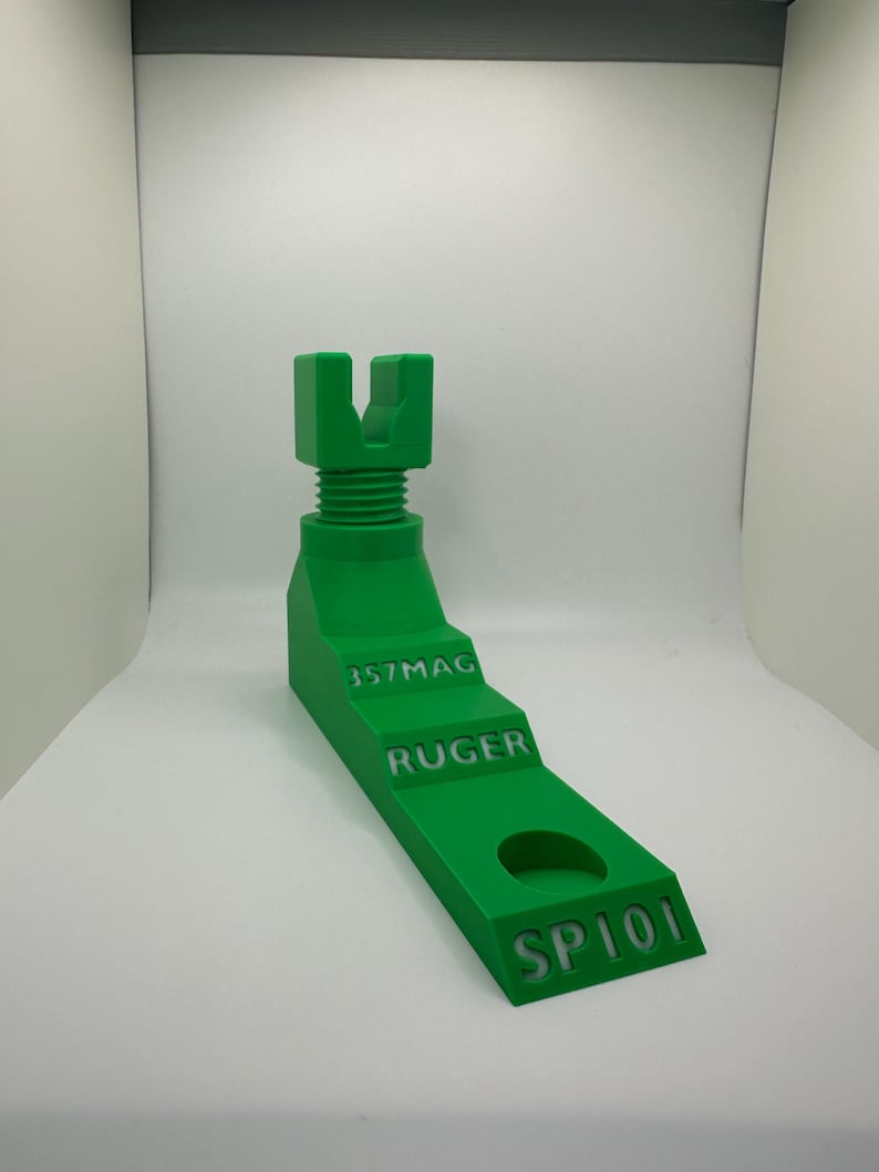 May include: A bright green, 3D-printed firearm stand. The stand features a stepped design with the engraved text "357MAG", "RUGER", and "SP101". It has a threaded top section and a circular hole. The stand is designed to hold a firearm.